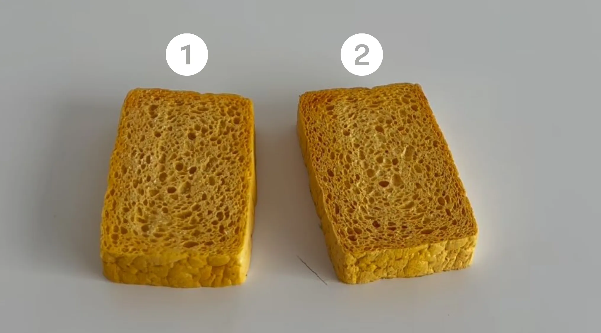 Two numbered slices resembling bread placed side by side, challenging the viewer to spot which one is real or cake.