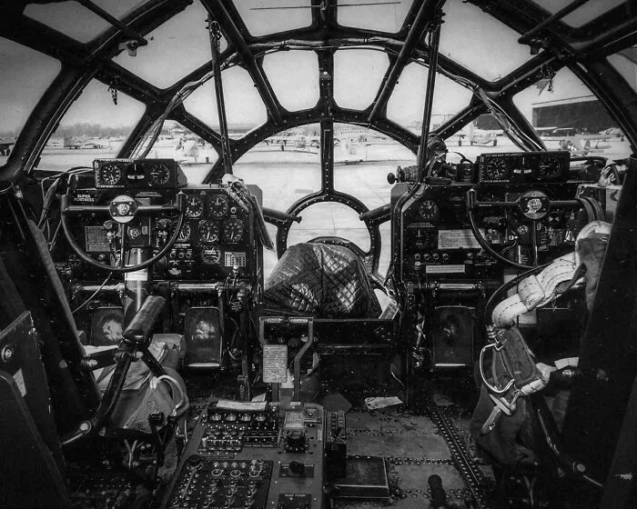 Vintage airplane cockpit with numerous dials and controls shown in an interesting historical photograph.