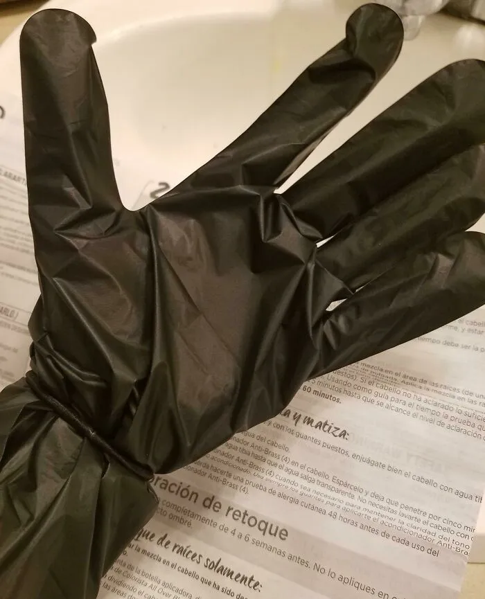 Black disposable glove on a hand over papers, an example of if it's stupid but it works then it's not stupid.