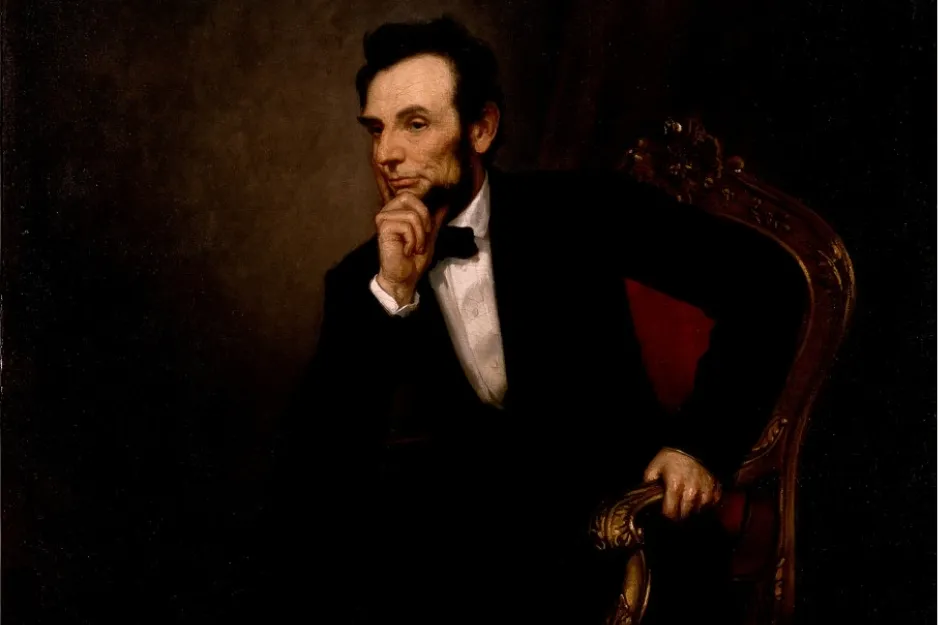 Portrait of Abraham Lincoln sitting in an ornate chair, dressed in black suit and white shirt with bow tie.