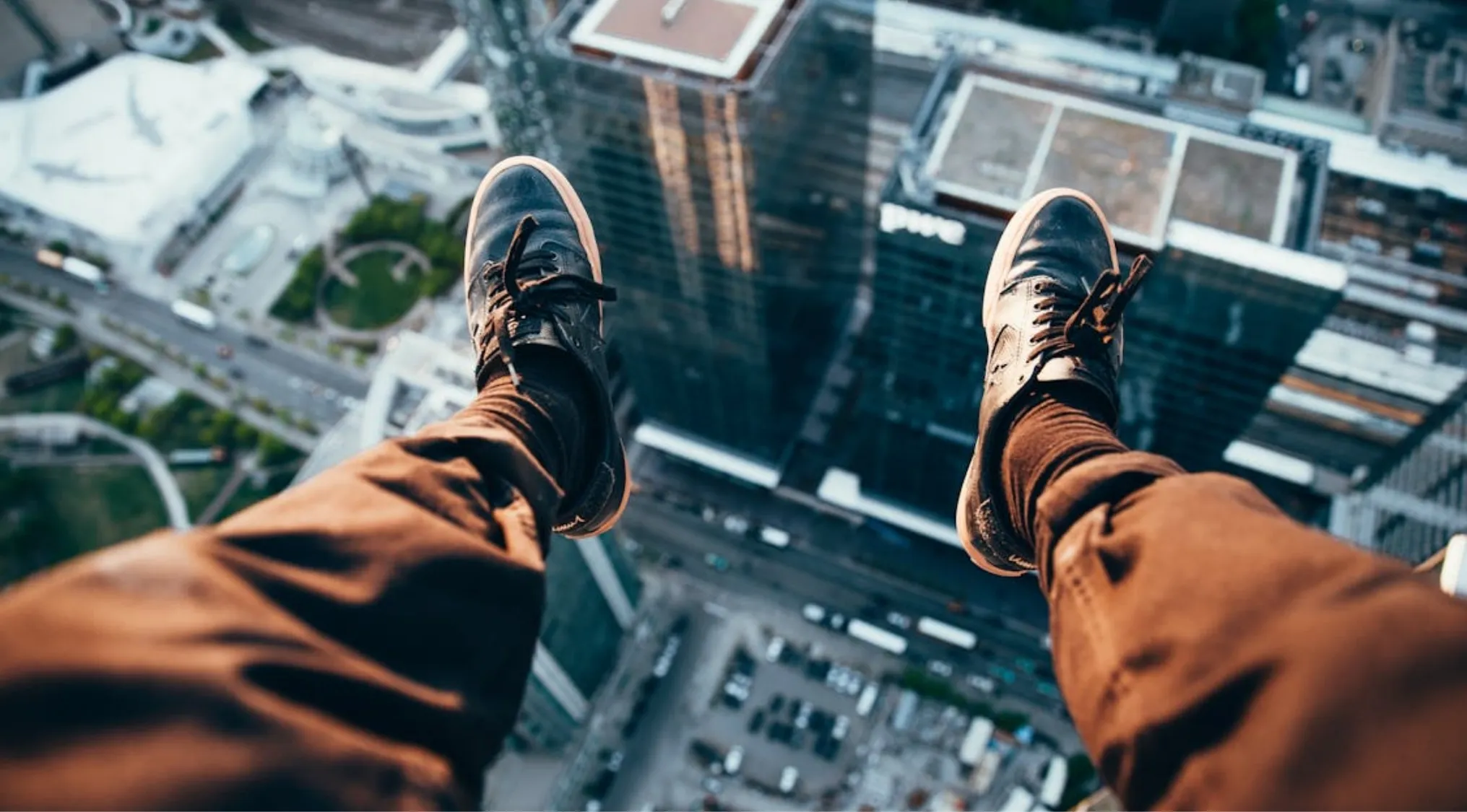 View of legs and shoes dangling high above a cityscape illustrating the fear of heights in a trivia night question.