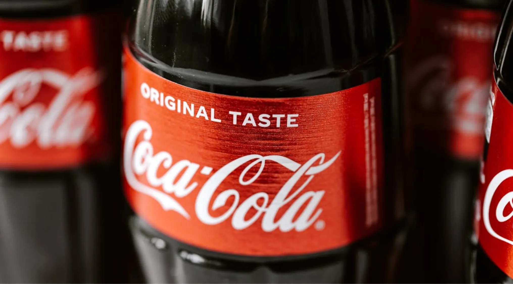 Close-up of Coca-Cola bottles with original taste labels highlighting trivia night facts about Coca-Cola.