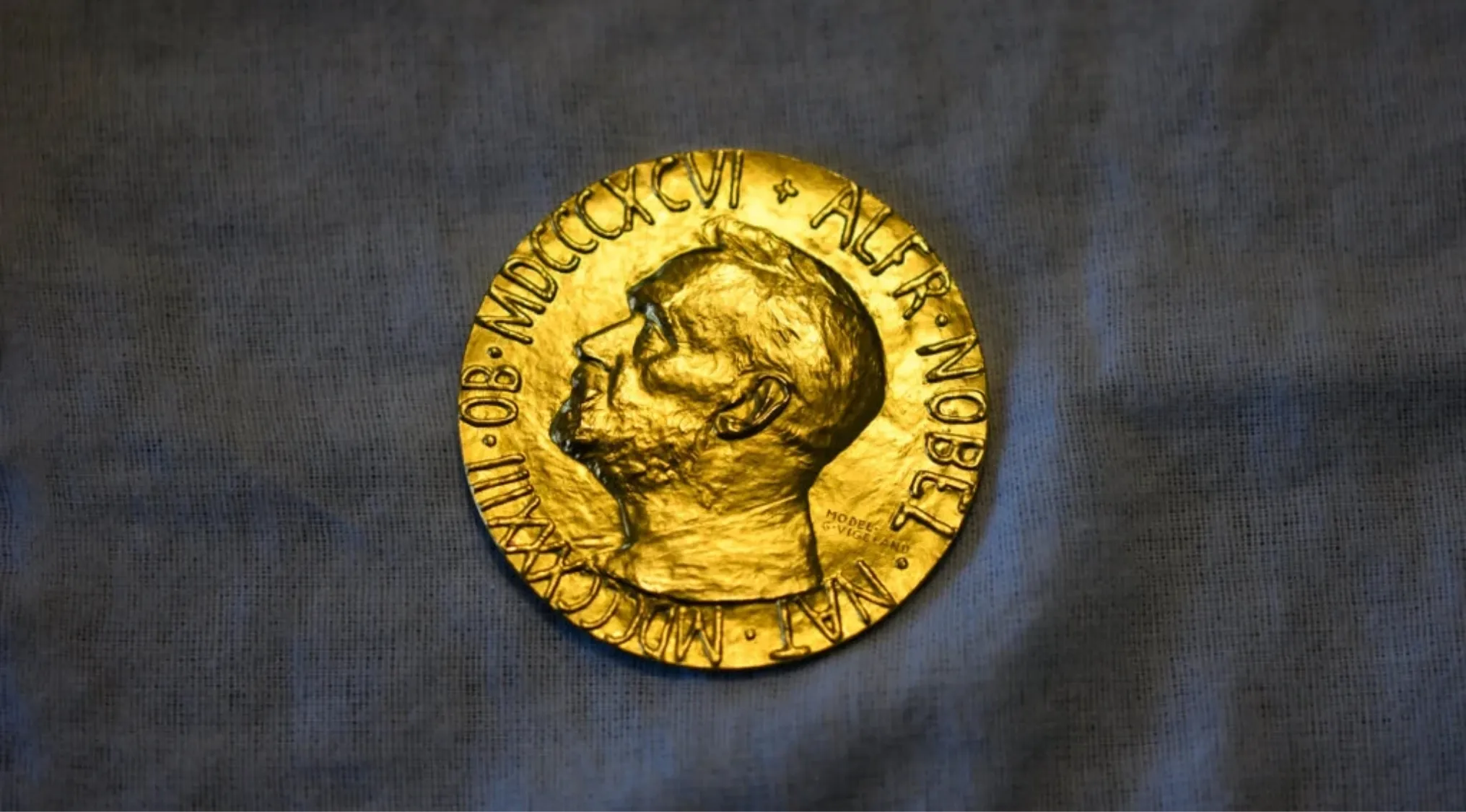 Gold Nobel Prize medal showing profile of Alfred Nobel on textured fabric background for trivia night.
