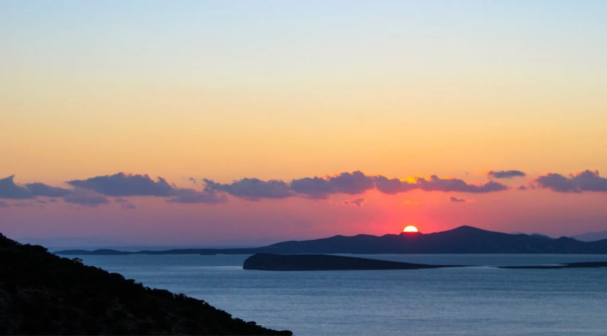 Sun rising over the ocean with islands silhouetted, illustrating the Land of the Rising Sun concept.