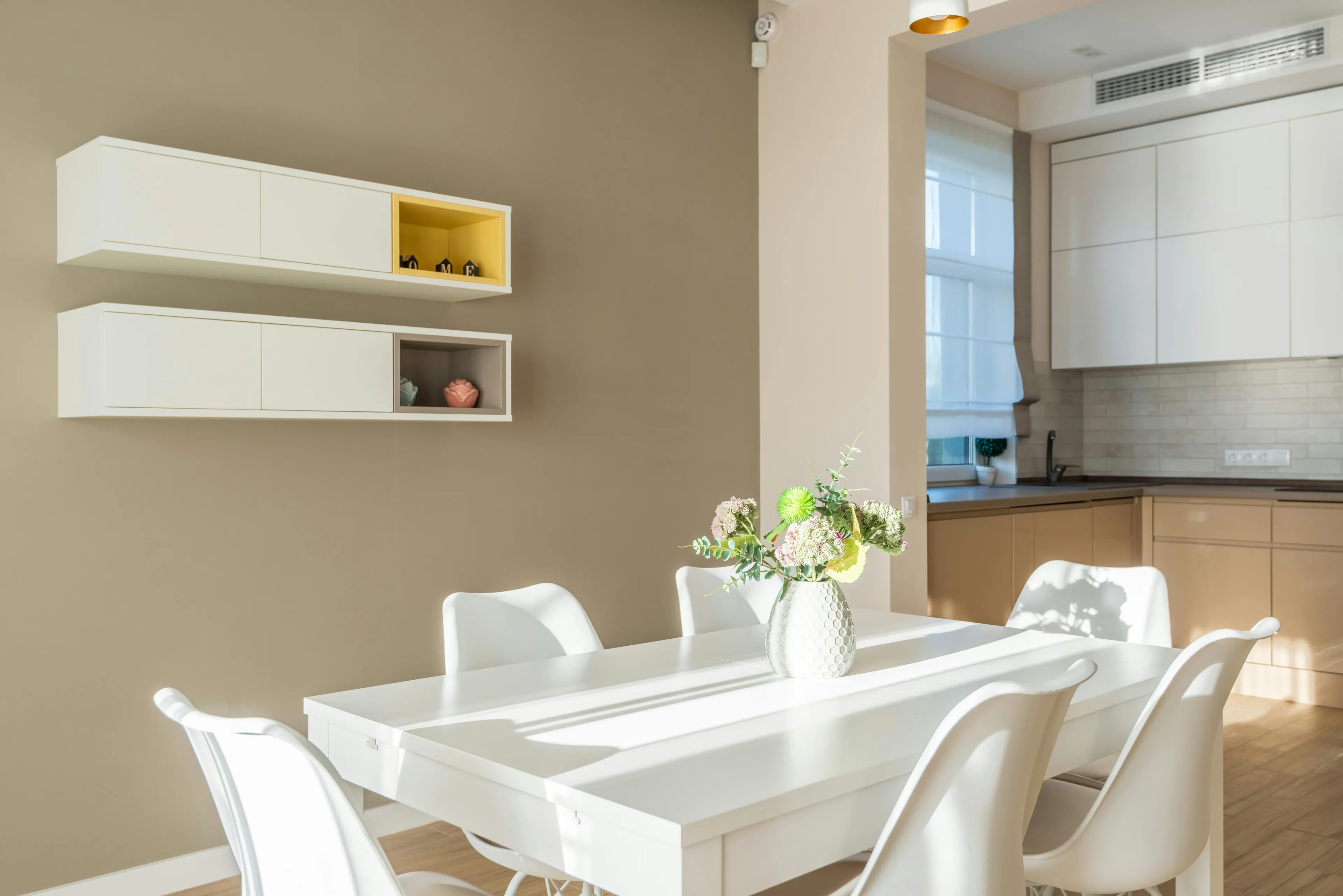 Bright dining area with sunlight showing refraction effect on white table and chairs in modern kitchen interior.