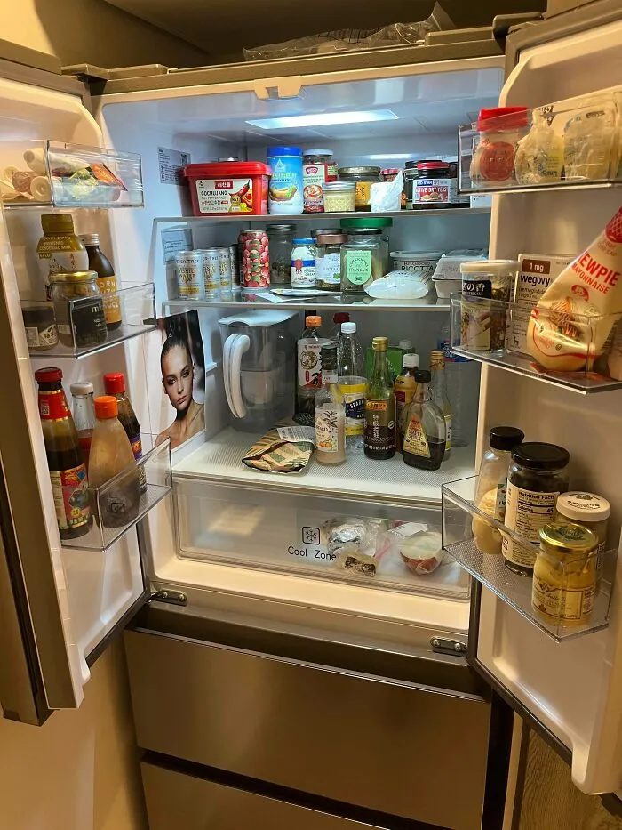 Open fridge filled with various condiments and food items, hinting at a surprising or horrifying discovery inside.