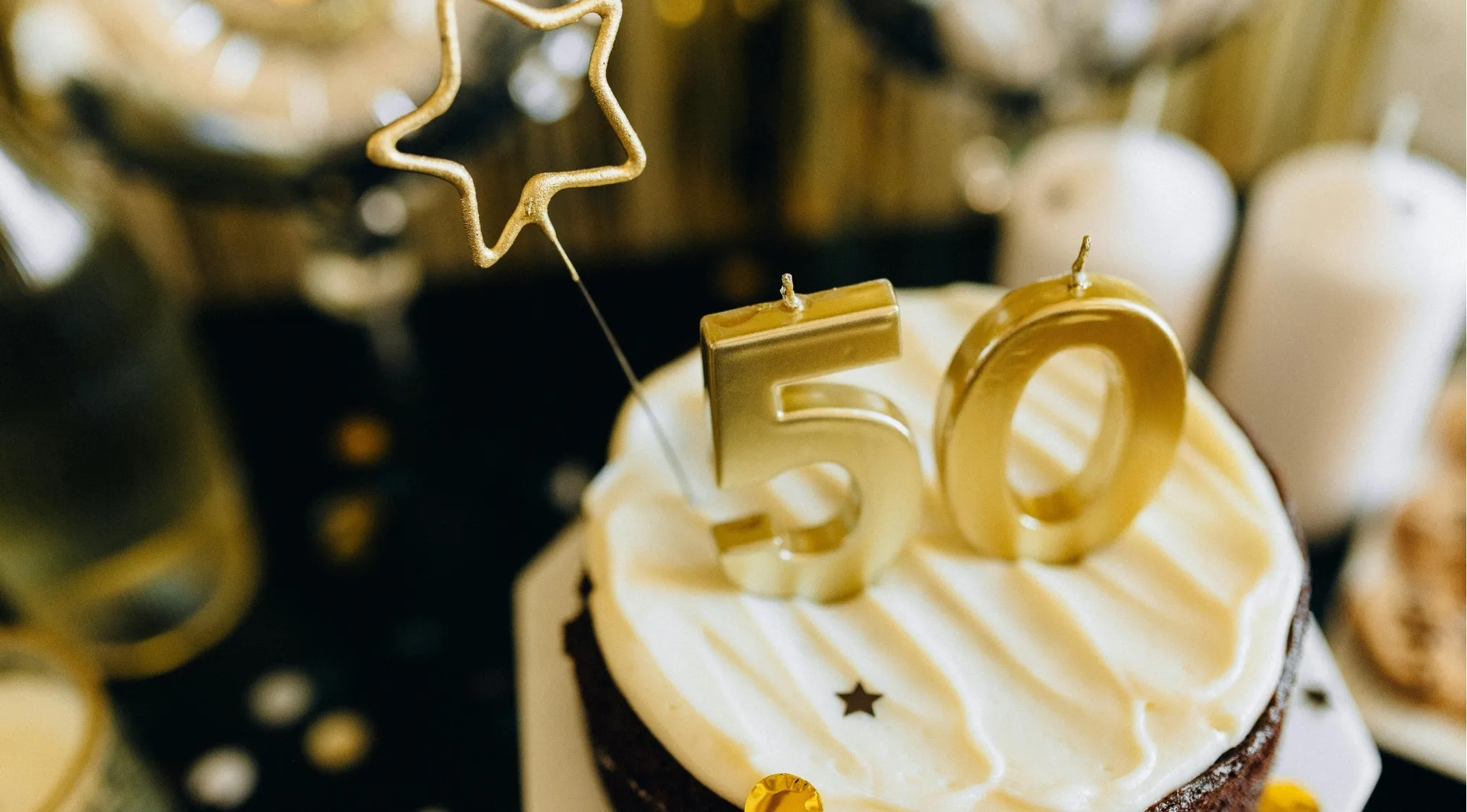 Gold 50th anniversary candles on a white frosted cake celebrating movies quiz anniversary edition milestone.