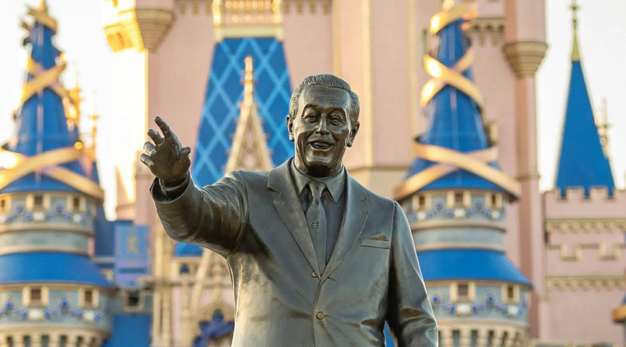 Statue of Walt Disney in front of a castle at a theme park, related to Disney movie quiz and anniversary edition.