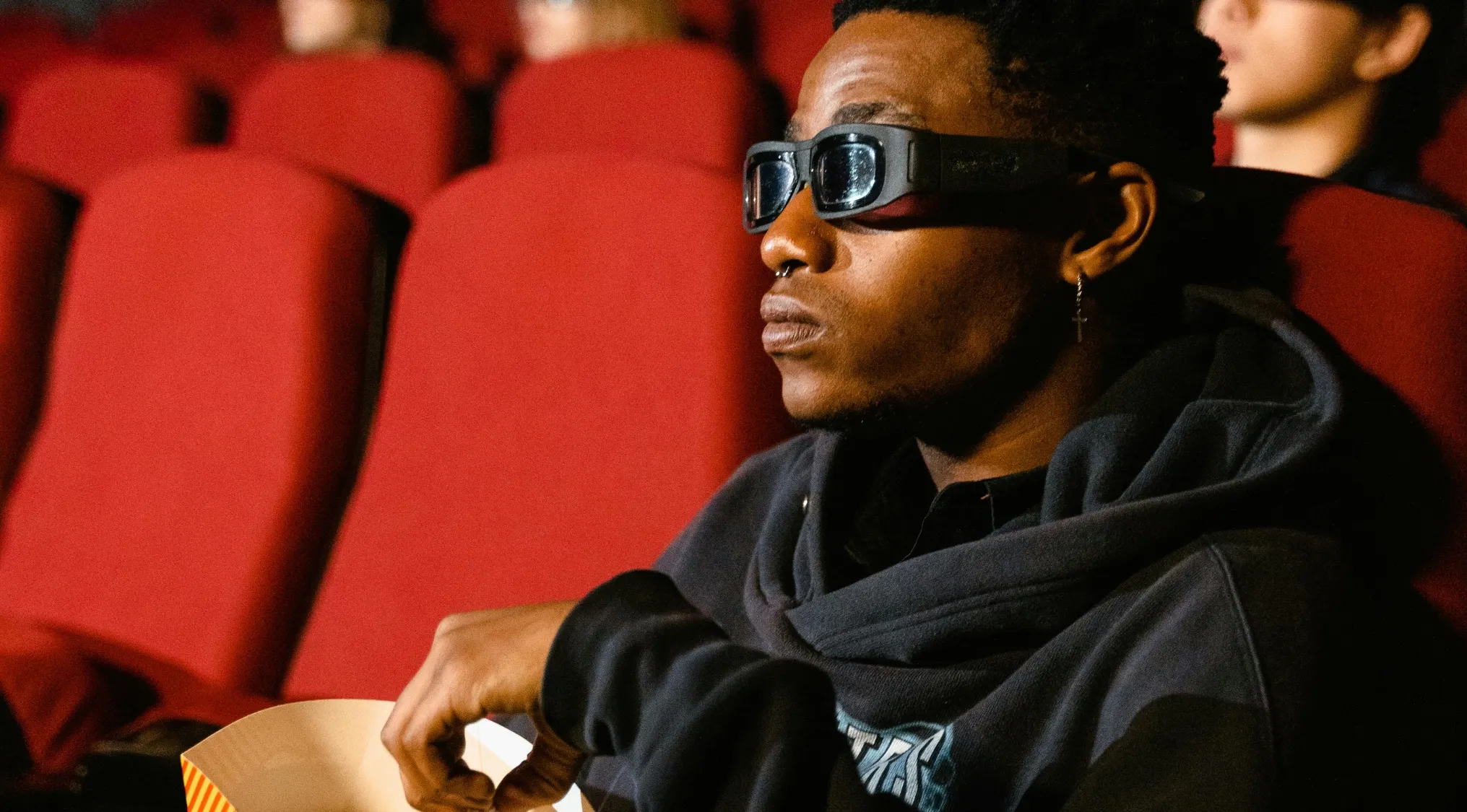 Person wearing 3D glasses in a theater, focused on a movie quiz about which movies were released in 2006.