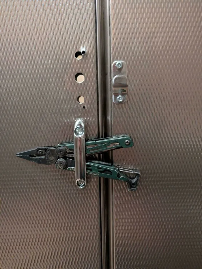 Improvised door lock using a multitool clamped on a metallic textured door illustrating clever if it works examples.