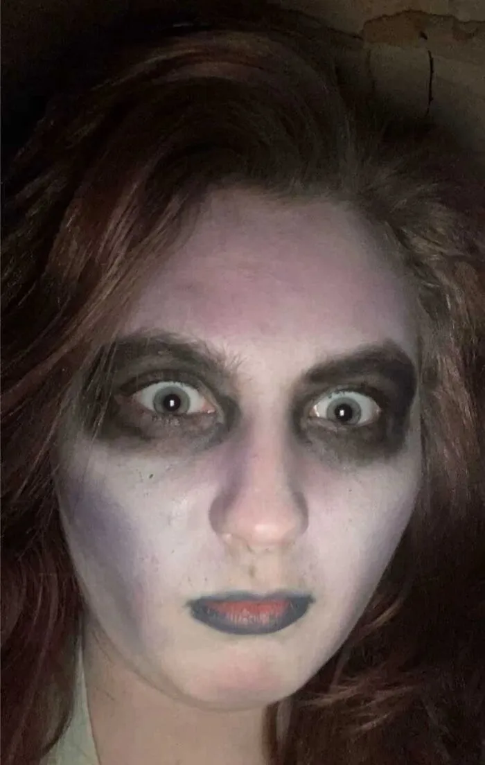 Person with stage makeup featuring dark eyeshadow and pale face, showing a magical yet mildly cursed look.