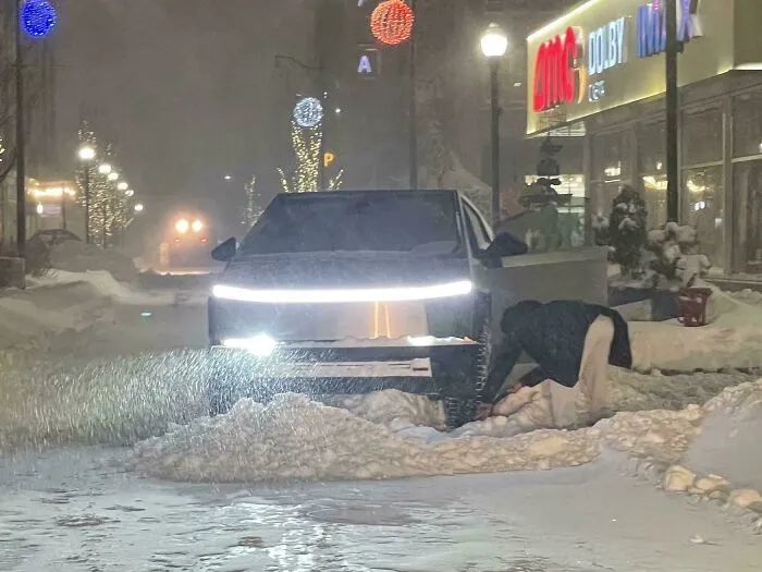 Electric truck clearing snow on a U.S. street at night during a heavy snowstorm hitting the area.