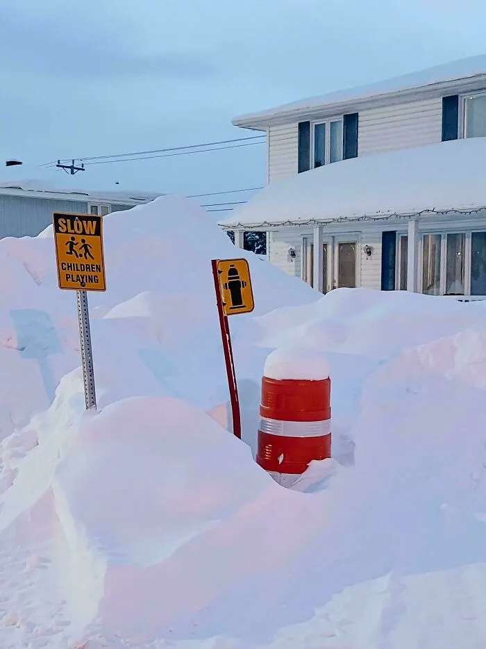 Snowstorm hitting the U.S. covers street signs and houses with deep snow drifts in a residential neighborhood.