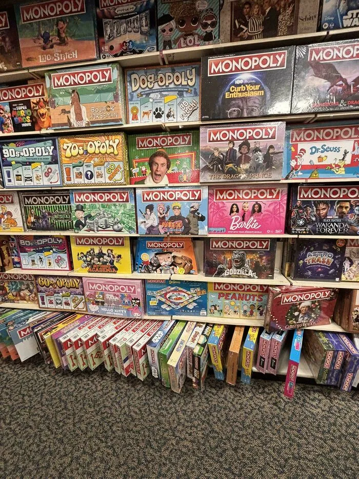 Shelves packed with multiple themed Monopoly board games illustrating consumerism in popular culture.