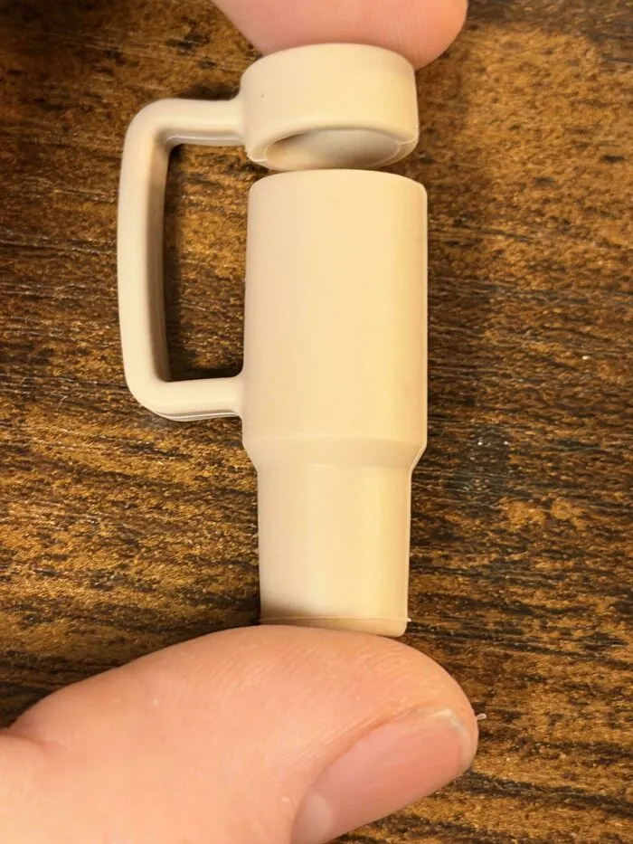 Minimalism tiny mug held between fingers on wooden surface