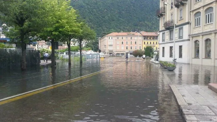 Flooded urban street with water covering roads and sidewalks, illustrating dystopian urban hell and challenges of modern life.