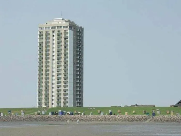 Tall residential building overlooking a barren beach with scattered trash, depicting dystopian urban hell and modern life.