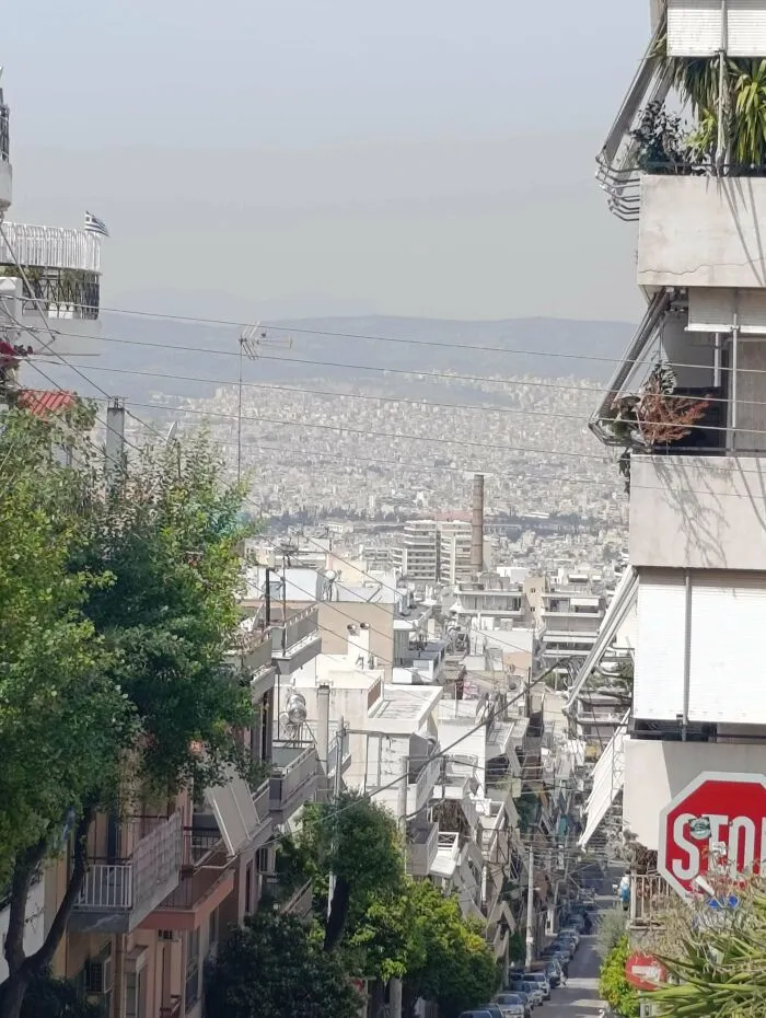 Dense urban residential buildings and crowded streets in a dystopian urban hell cityscape under a hazy sky.