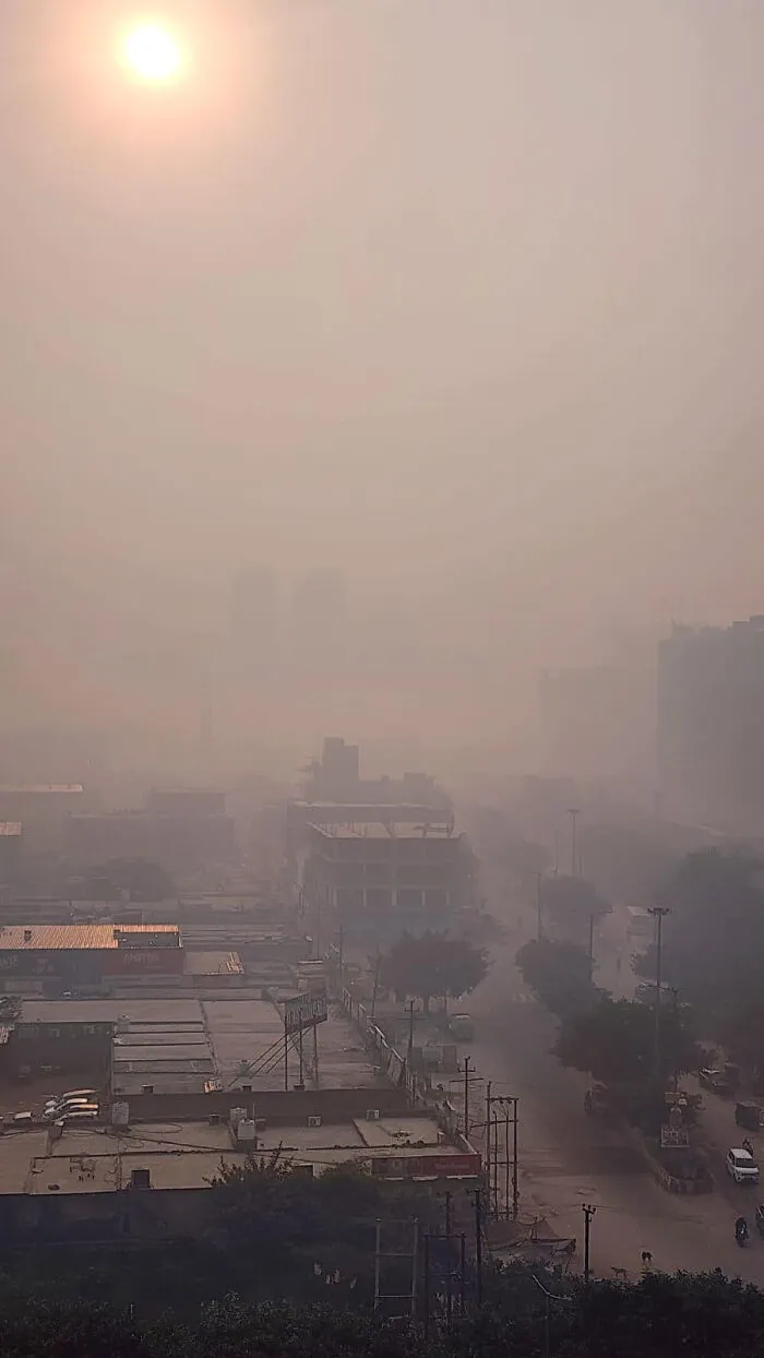 Smog-covered urban landscape with barely visible buildings and muted sunlight showing dystopian urban hell conditions.