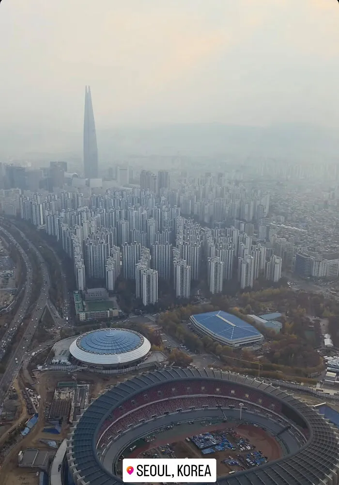 Aerial view of Seoul, Korea showing dense high-rise buildings and urban hell atmosphere under hazy sky.