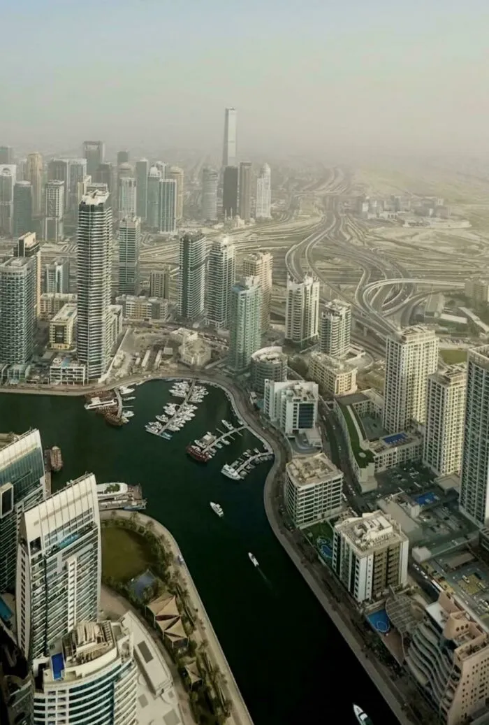 Aerial view of a dense urban area with high-rise buildings and highways under a hazy sky in a dystopian urban hell.