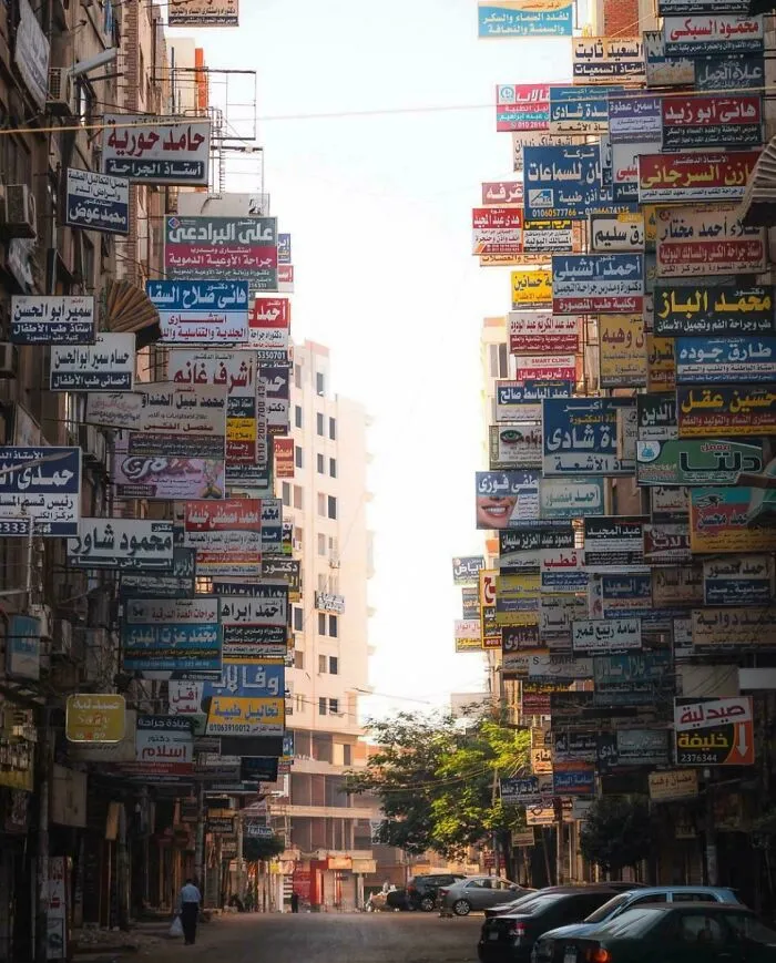 Dystopian urban hell street crowded with countless colorful advertising signs in a narrow city alleyway.