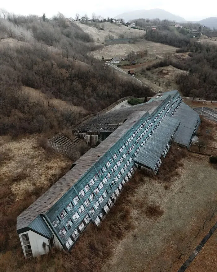 Abandoned dystopian urban hell building in a bleak rural landscape, illustrating the true price of modern life decay.