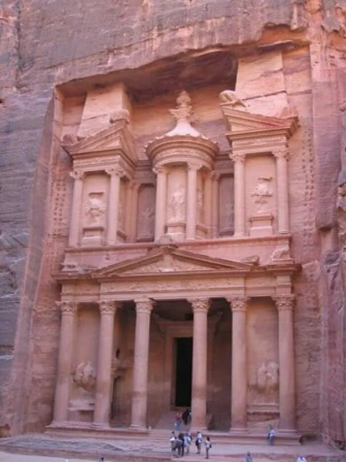 An extremely large ancient stone building carved into a cliff face, showing scary and eerie human scale.