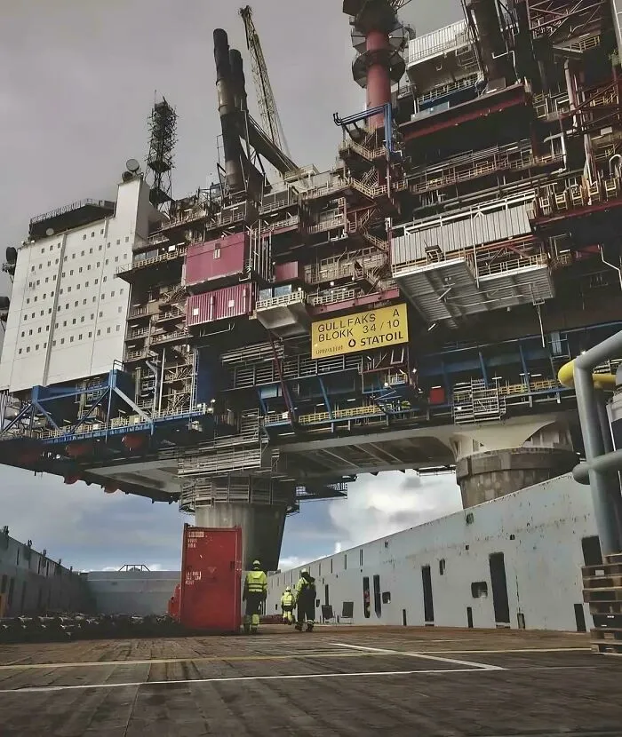 Extremely large offshore oil rig towering over workers, highlighting the scary and eerie scale of industrial structures.