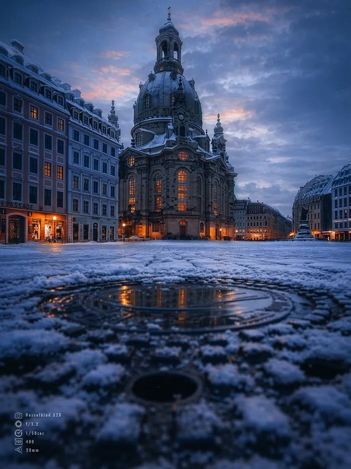 Beautiful architecture: Dresden Frauenkirche at dusk, illuminated with warm lights, surrounded by snow.