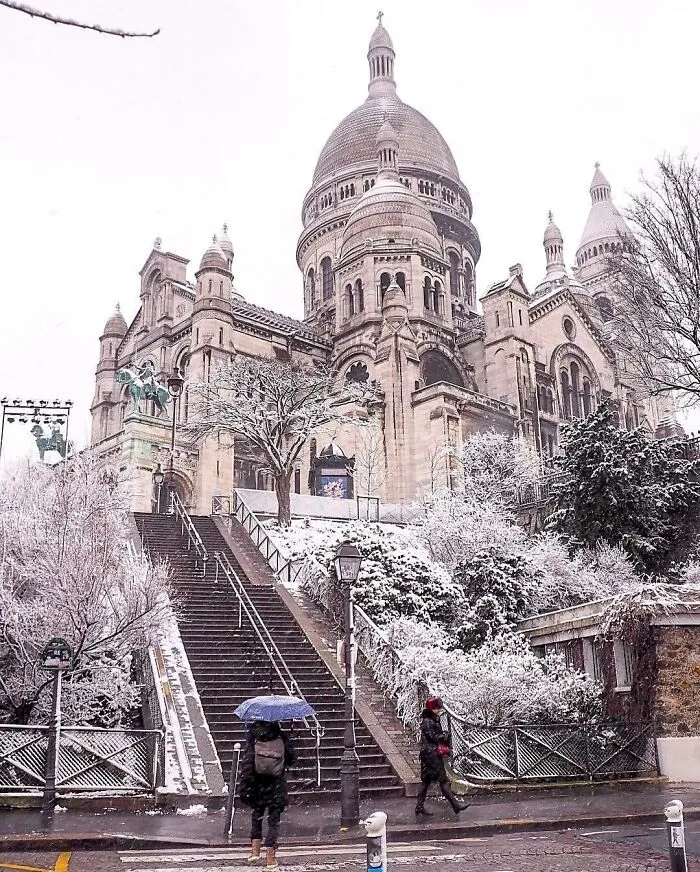 Beautiful architecture: Sacré-Cœur Basilica in Paris covered in snow, with people walking below.