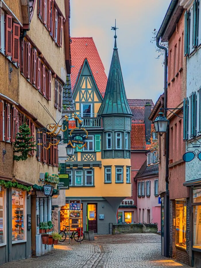 Charming, beautiful architecture of a narrow European street with colorful buildings and a unique pointed tower.
