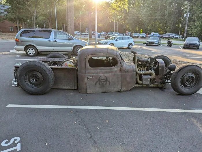 Rusty, customized rat rod car with exposed engine and biohazard symbol, showing extreme redneck engineering creativity.