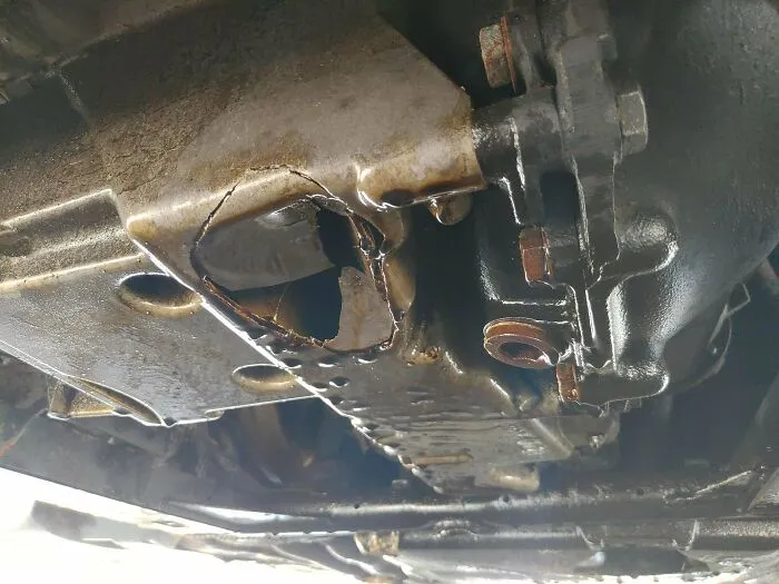 Close-up of vehicle metal part with a poorly welded and patched hole, showcasing redneck engineering repair.