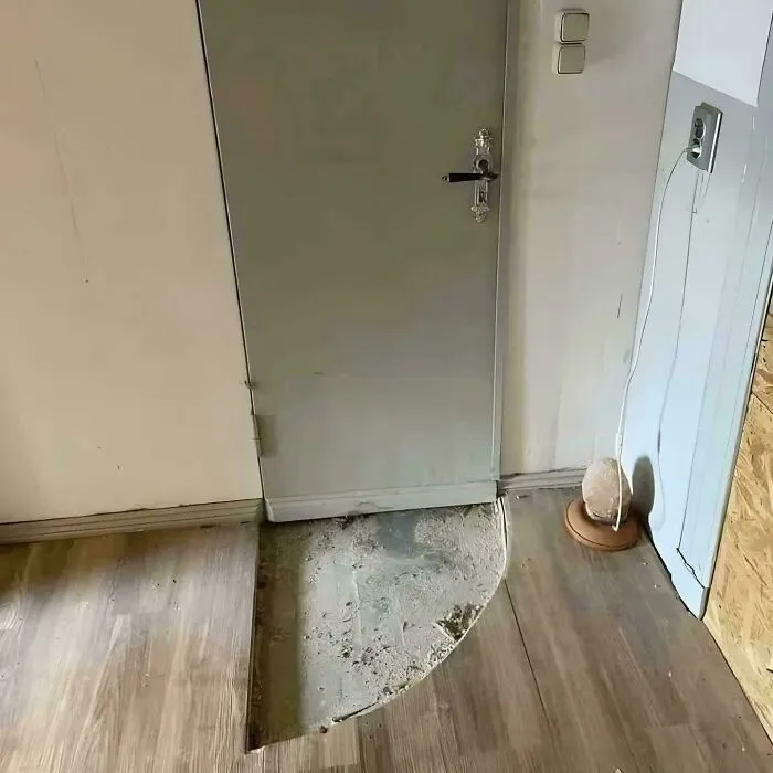 Floor cutout around door with uneven edges and exposed concrete, an example of redneck engineering in home construction.