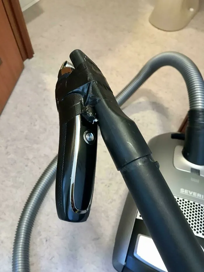Vacuum cleaner handle secured with black tape in a redneck engineering fix that might shock actual engineers.