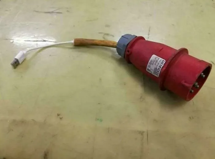 Improvised redneck engineering power adapter made by connecting a USB cable to a heavy-duty industrial plug on a worn surface.