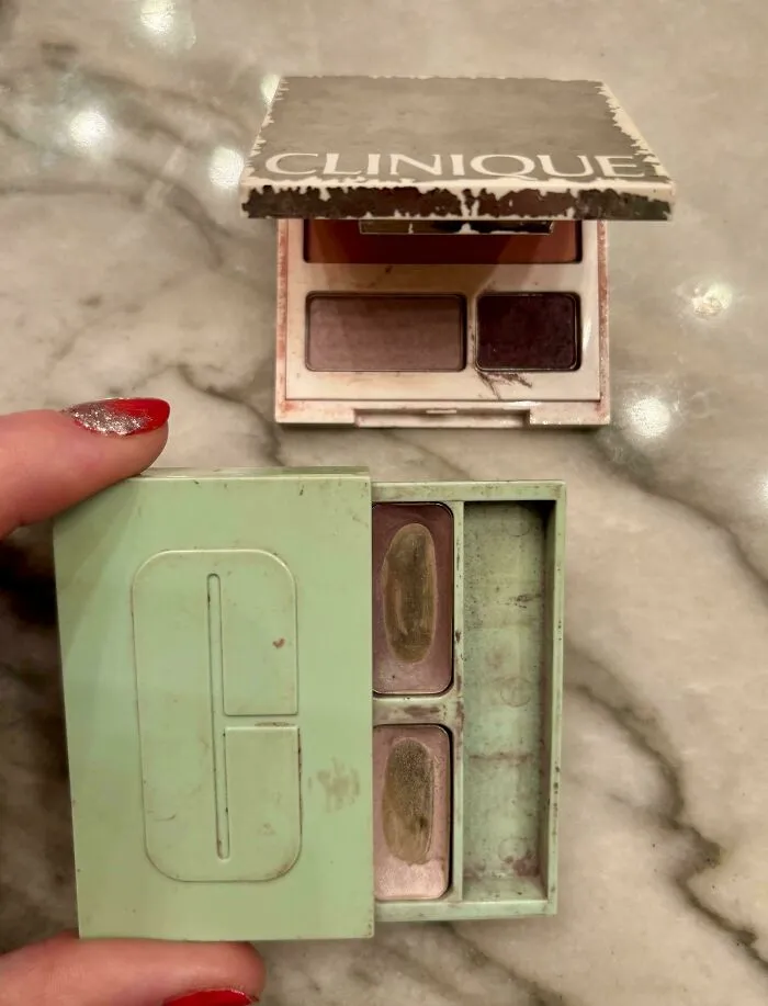 Vintage Clinique makeup palettes held on a marble surface, evoking 90s nostalgia and childhood memories with worn packaging.