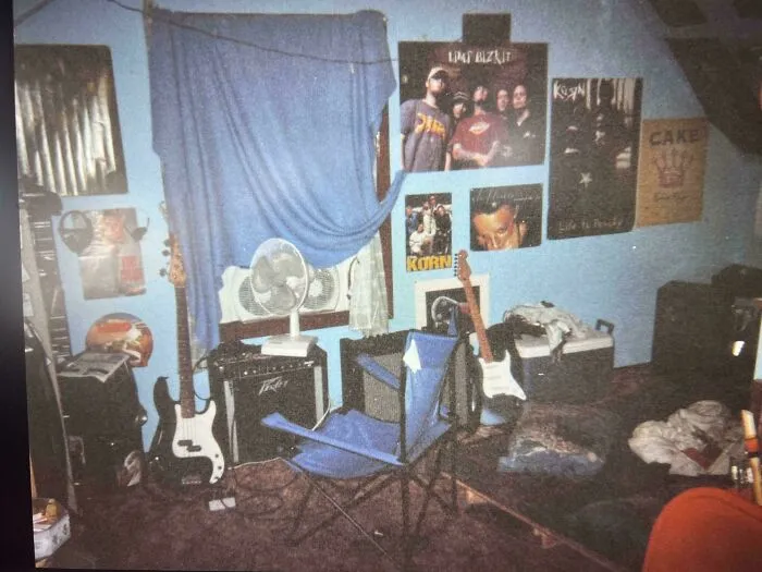 90s childhood bedroom with band posters, electric guitars, amplifier, and a folding chair in a nostalgic setting.