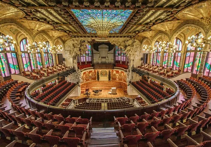An ornate concert hall with stained glass and detailed ceilings, a stunning example of beautiful architecture.