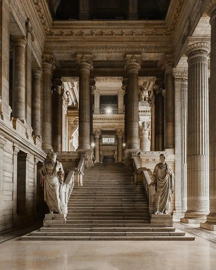 Inside a majestic building with a grand staircase and numerous columns, an example of beautiful architecture.