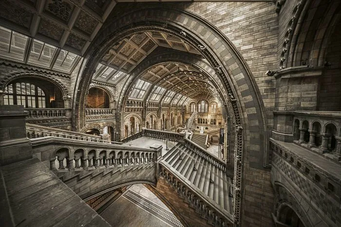 Interior view of a grand hall with arched ceilings and elaborate staircases, featuring beautiful architecture.