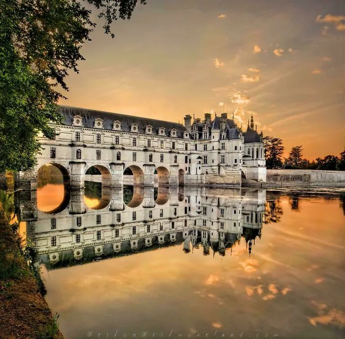 Stunning Château de Chenonceau, beautiful architecture reflected in the water at sunset.
