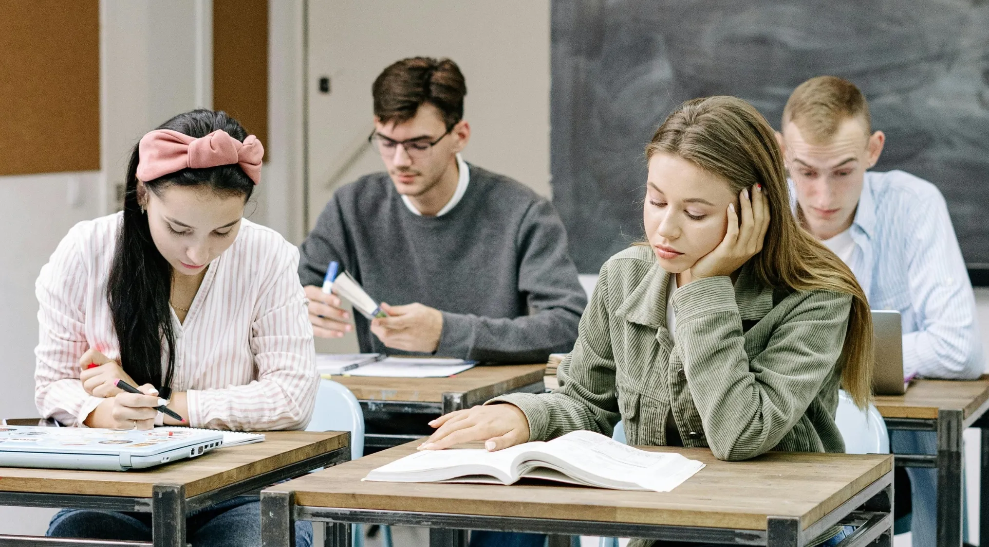 Four students in classroom focused on school test, each needing notebooks and pencils for UK 11 plus exam practice.