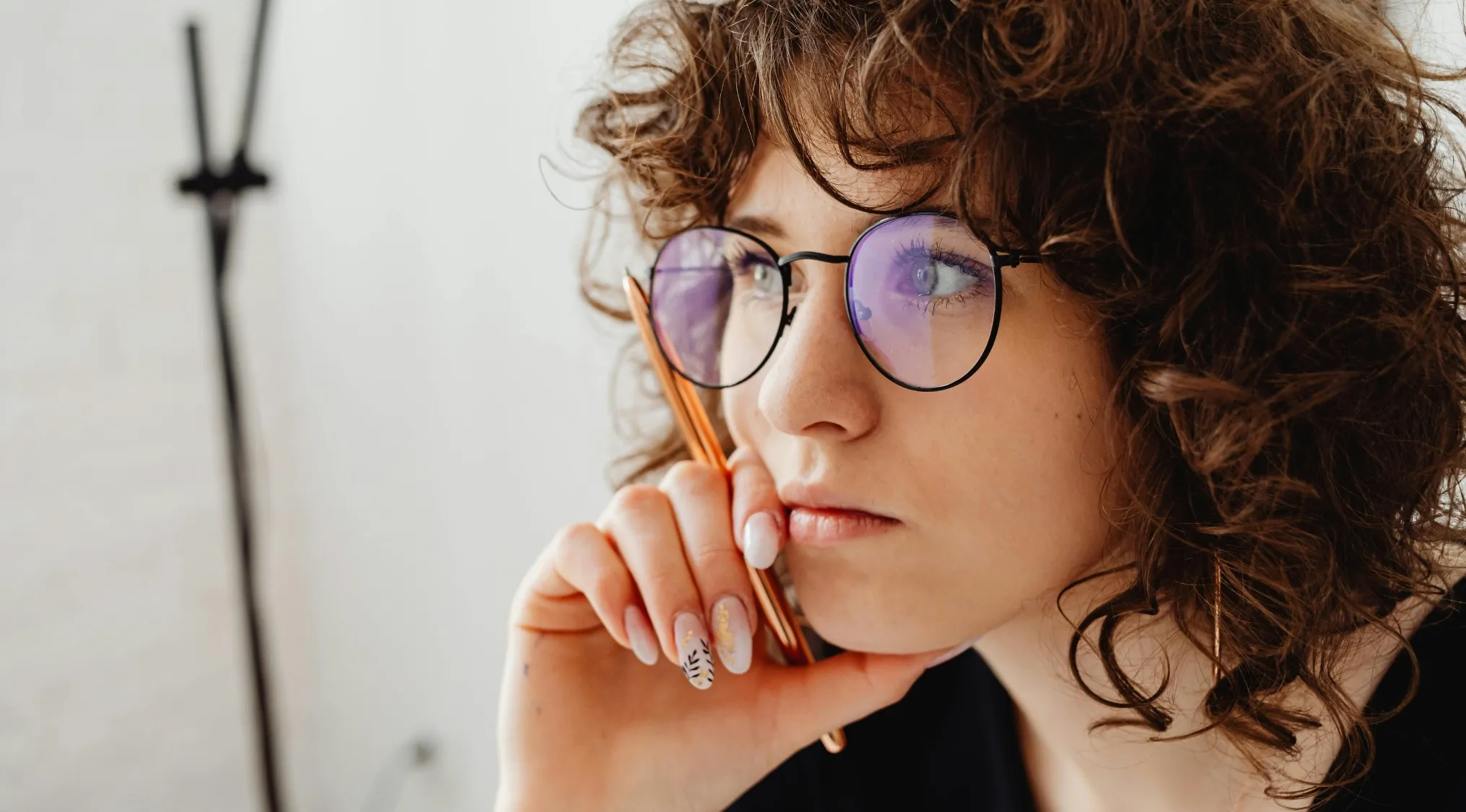 Young woman with glasses holding a pen, deep in thought while preparing for UK 11+ school test math question.