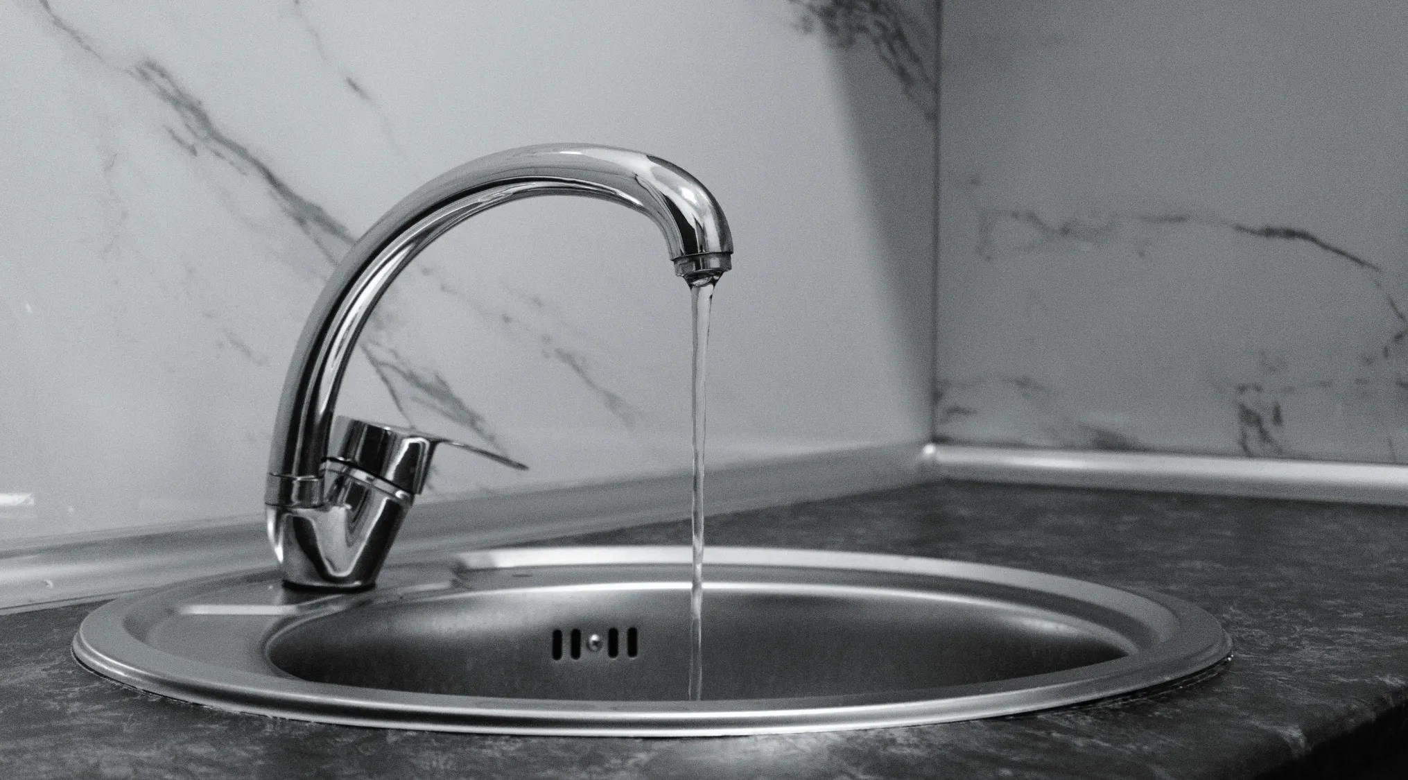 A kitchen tap dripping water slowly into a sink, illustrating a UK 11+ school test water leakage problem.