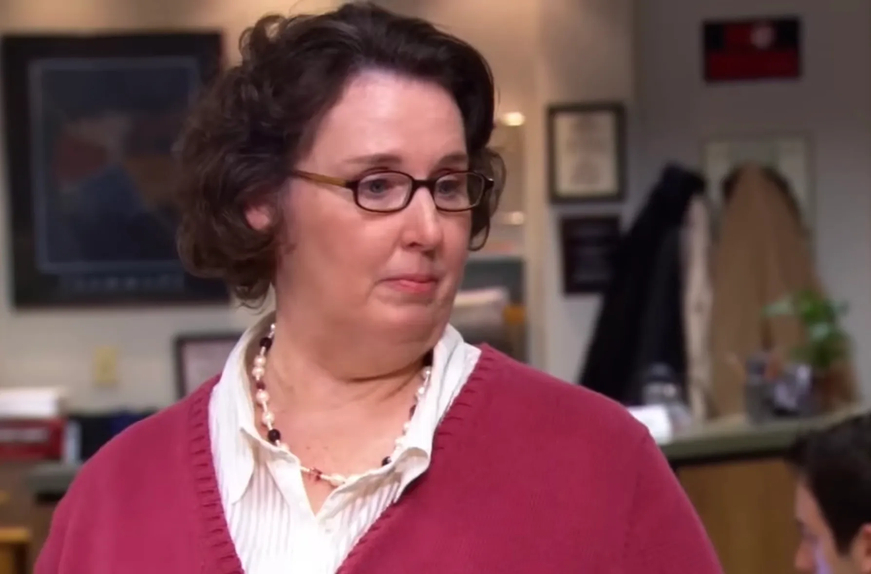 Woman in a red sweater and glasses portraying Phyllis Vance, receptionist and office administrator in the U.S. version of The Office.