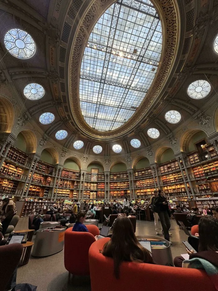 Interior of a beautiful library, showcasing stunning architecture with a grand glass ceiling and numerous bookshelves.
