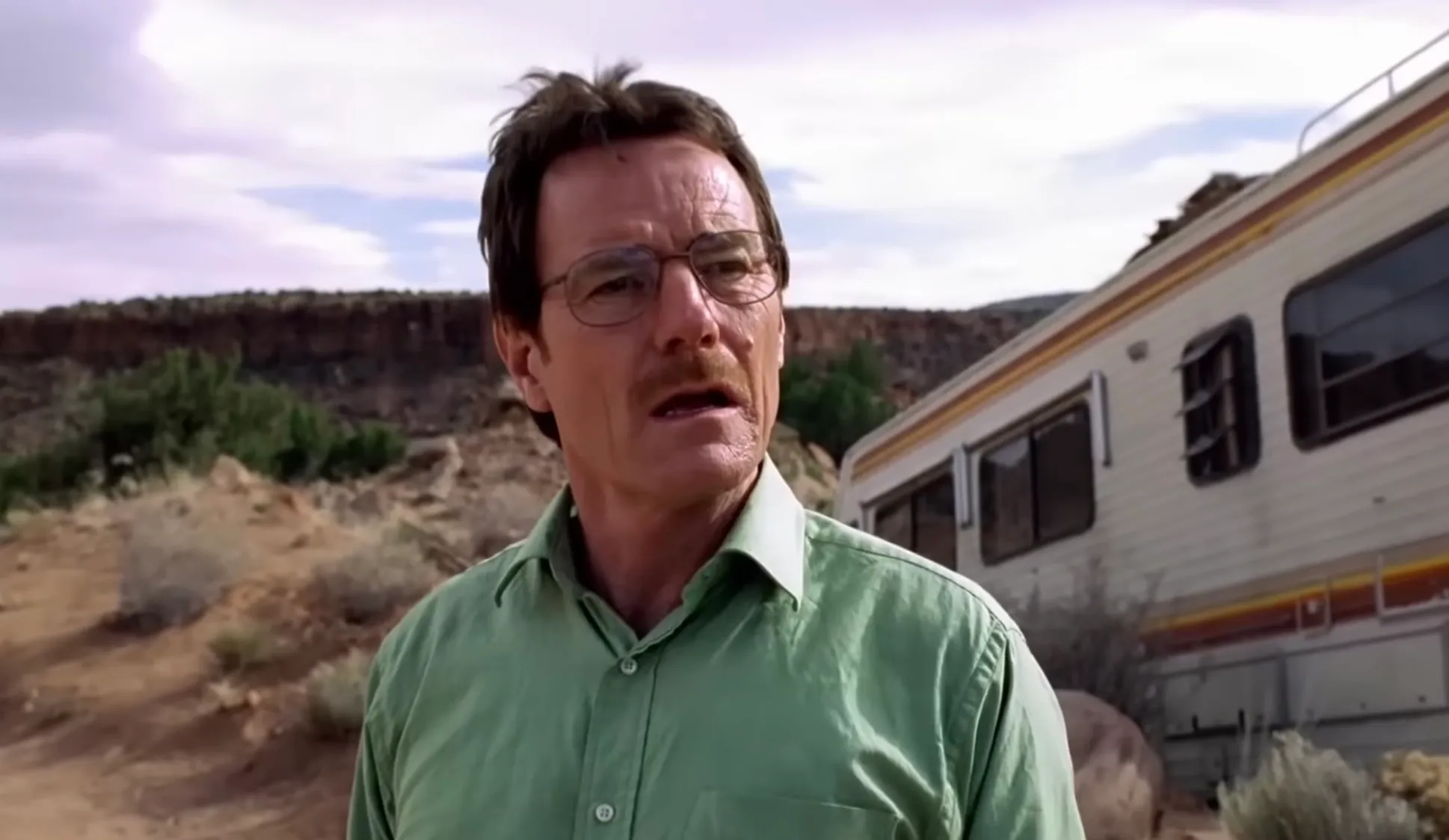 Bryan Cranston as the morally conflicted chemistry teacher-turned-criminal in Breaking Bad wearing glasses and a green shirt outdoors.