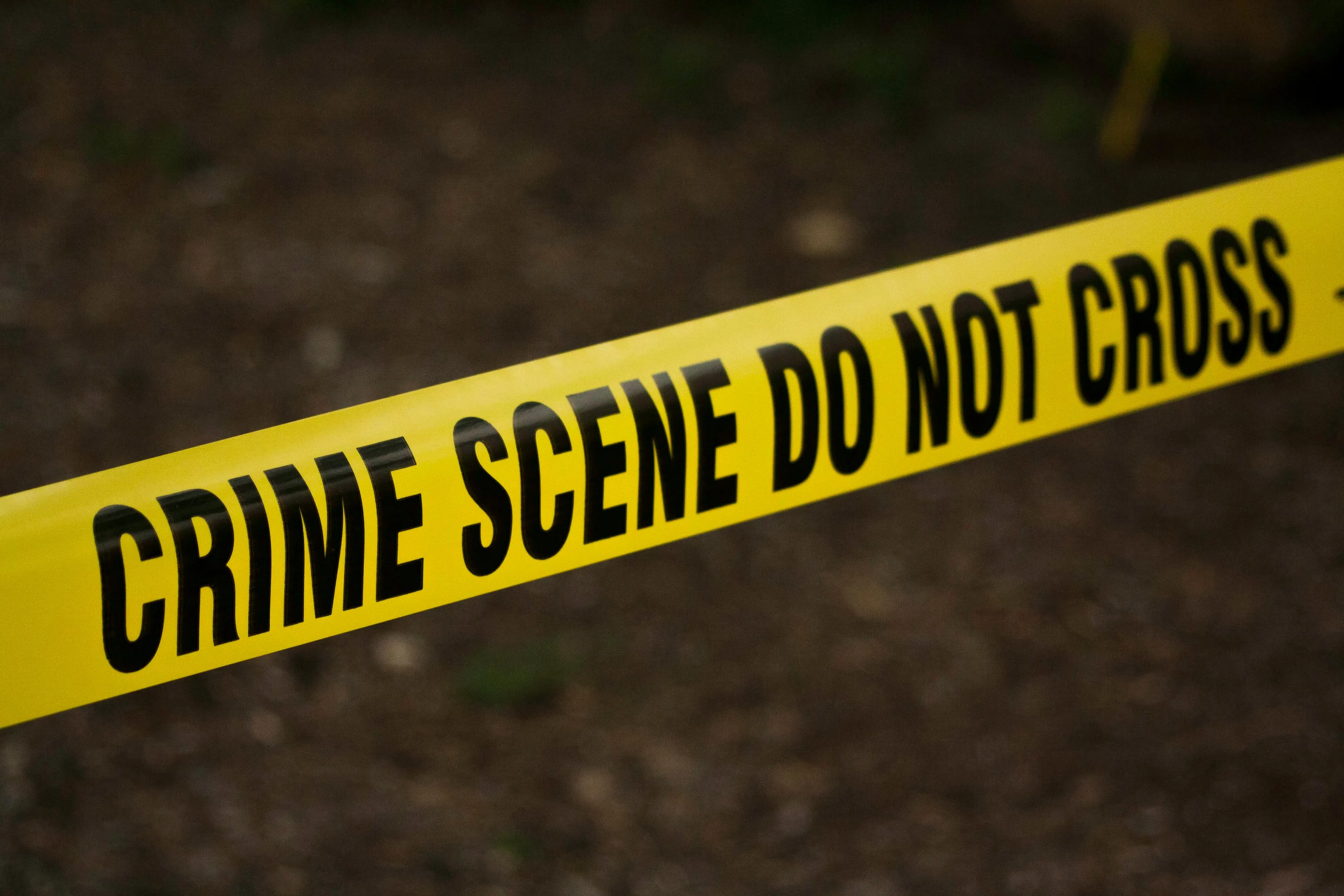 Yellow crime scene tape with black text warning not to cross at a crime scene in a crime drama series setting.